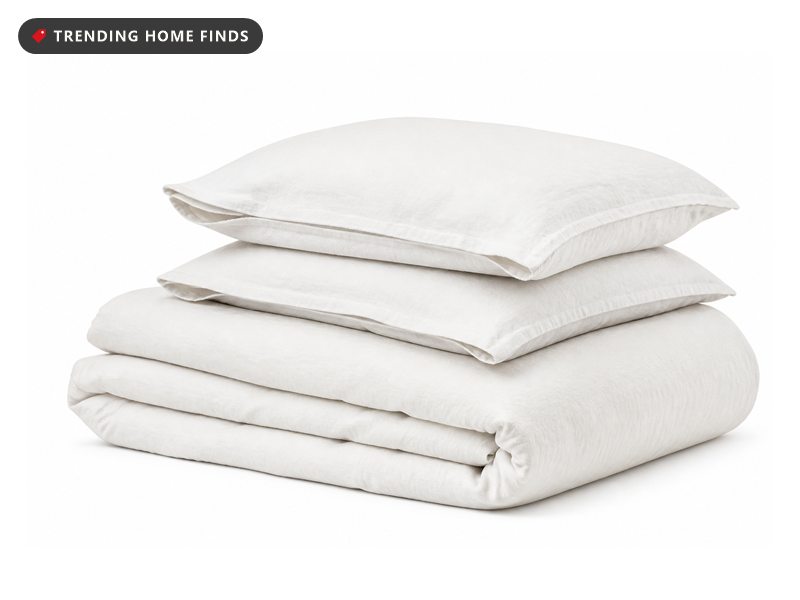 A natural white washed cotton duvet cover folded square with two matching pillow shams stacked on top.