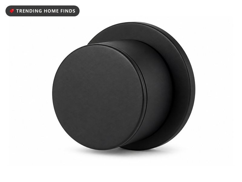 A round matte black retrofit smart lock with a flat circular front face and a mounting plate.