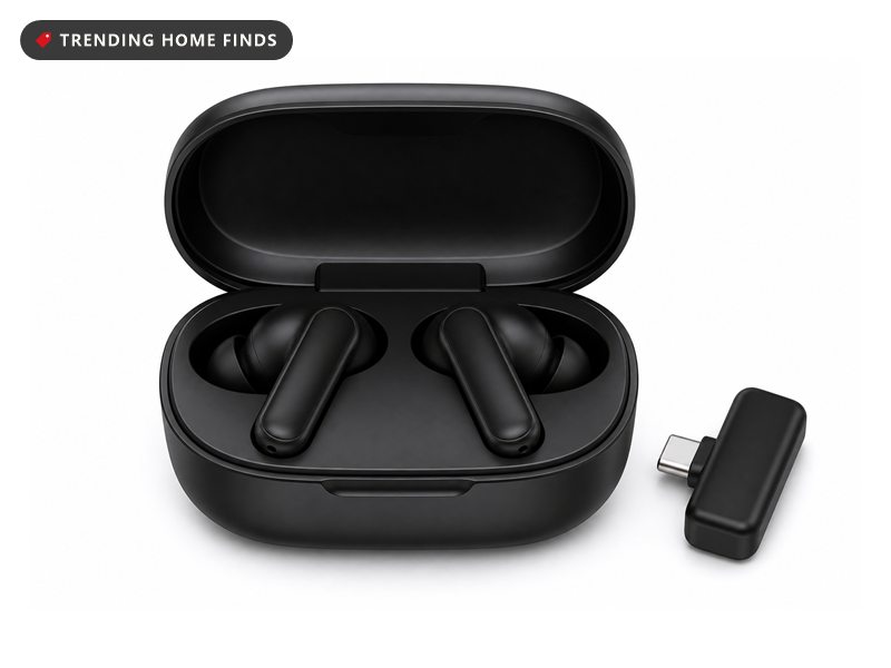Black wireless earbuds seated in an open black charging case with a small dongle beside it.