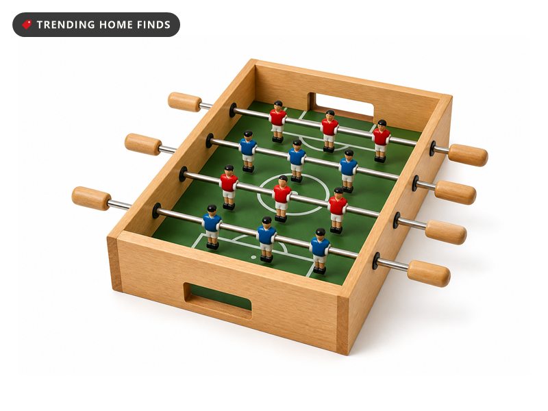 A compact wooden tabletop foosball game with a green field, small goals and rows of players on steel rods.
