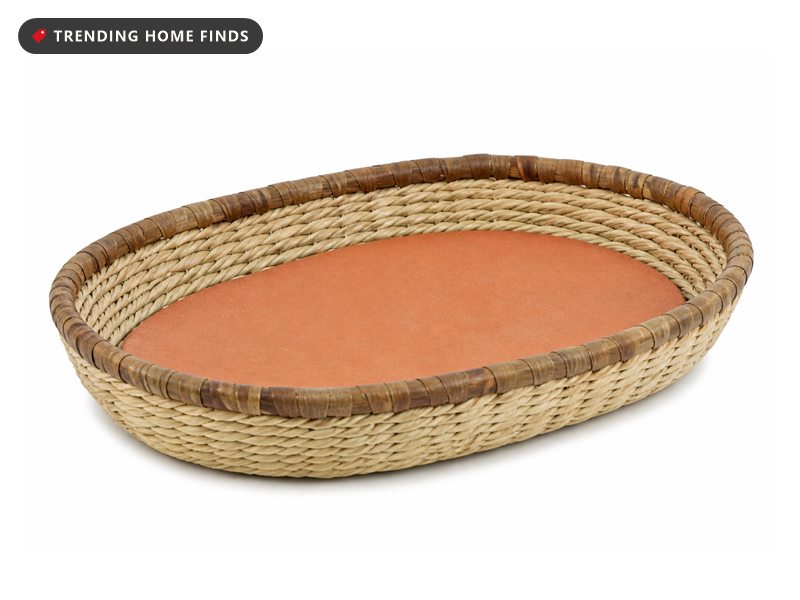 An oval handwoven grass bread basket with a palm wrapped rim and a flat terracotta warming tile inside.